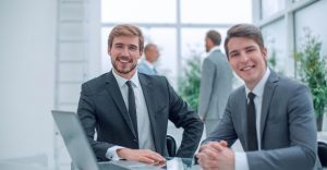 Two smiling businessmen sitting and looking confidently in camera